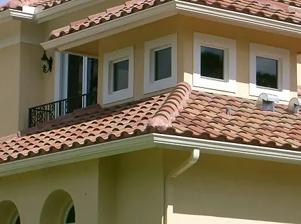 White gutter and downspout under a barrel tile roof