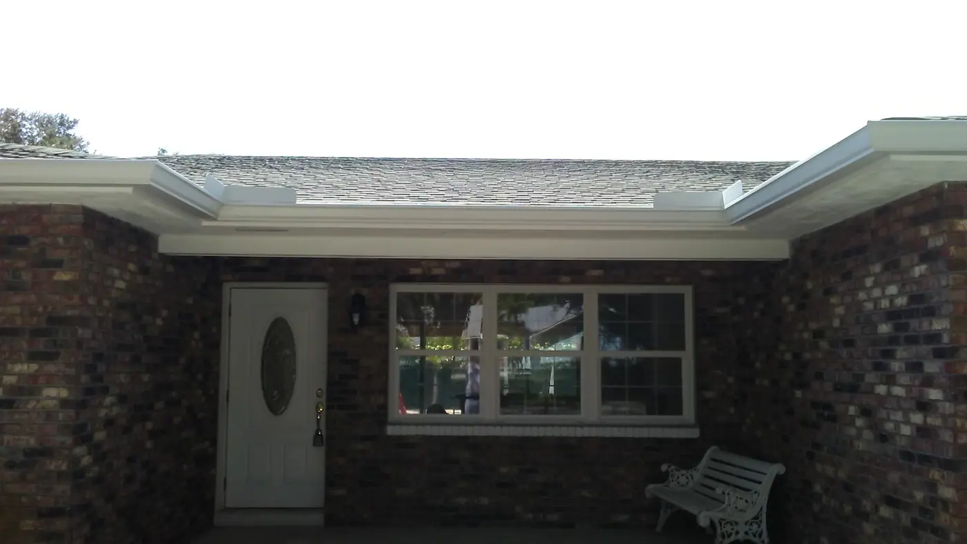 White seamless gutter across the front of a brick ranch home