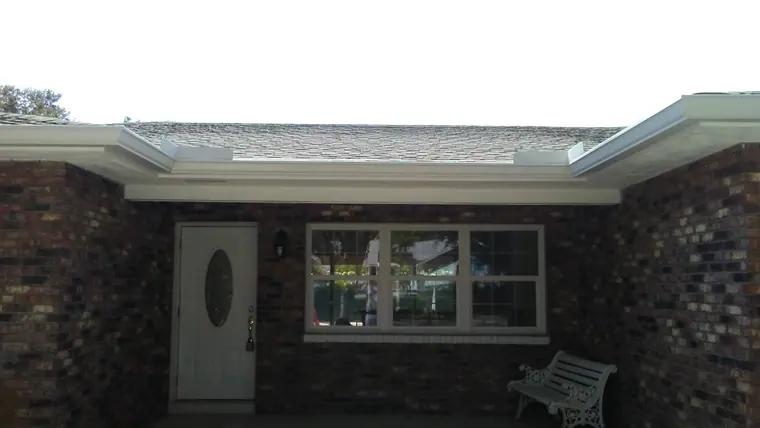 White seamless gutter across the front of a brick ranch home