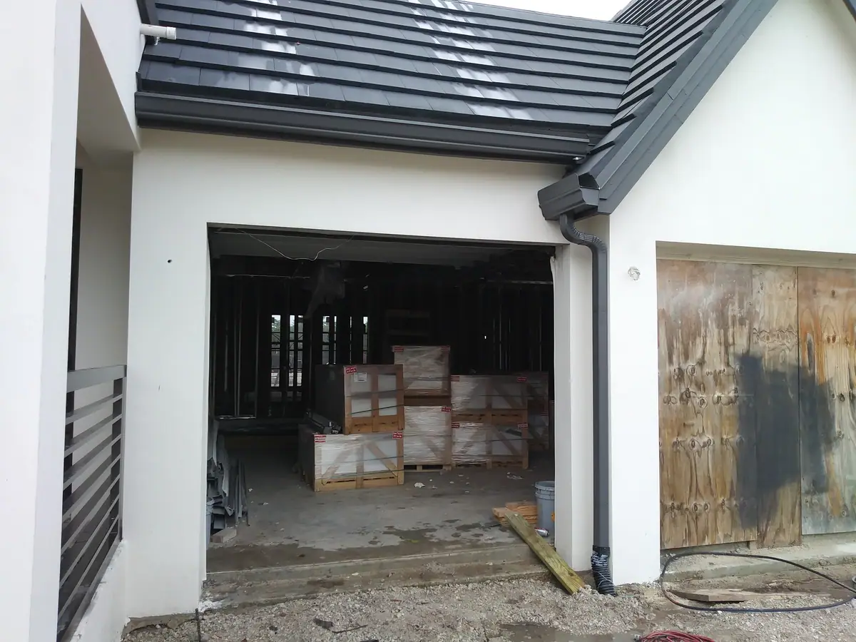 Dark gutter and downspout on a new white stucco home under construction