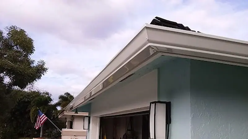 White seamless gutter along the roofline of a light blue stucco home